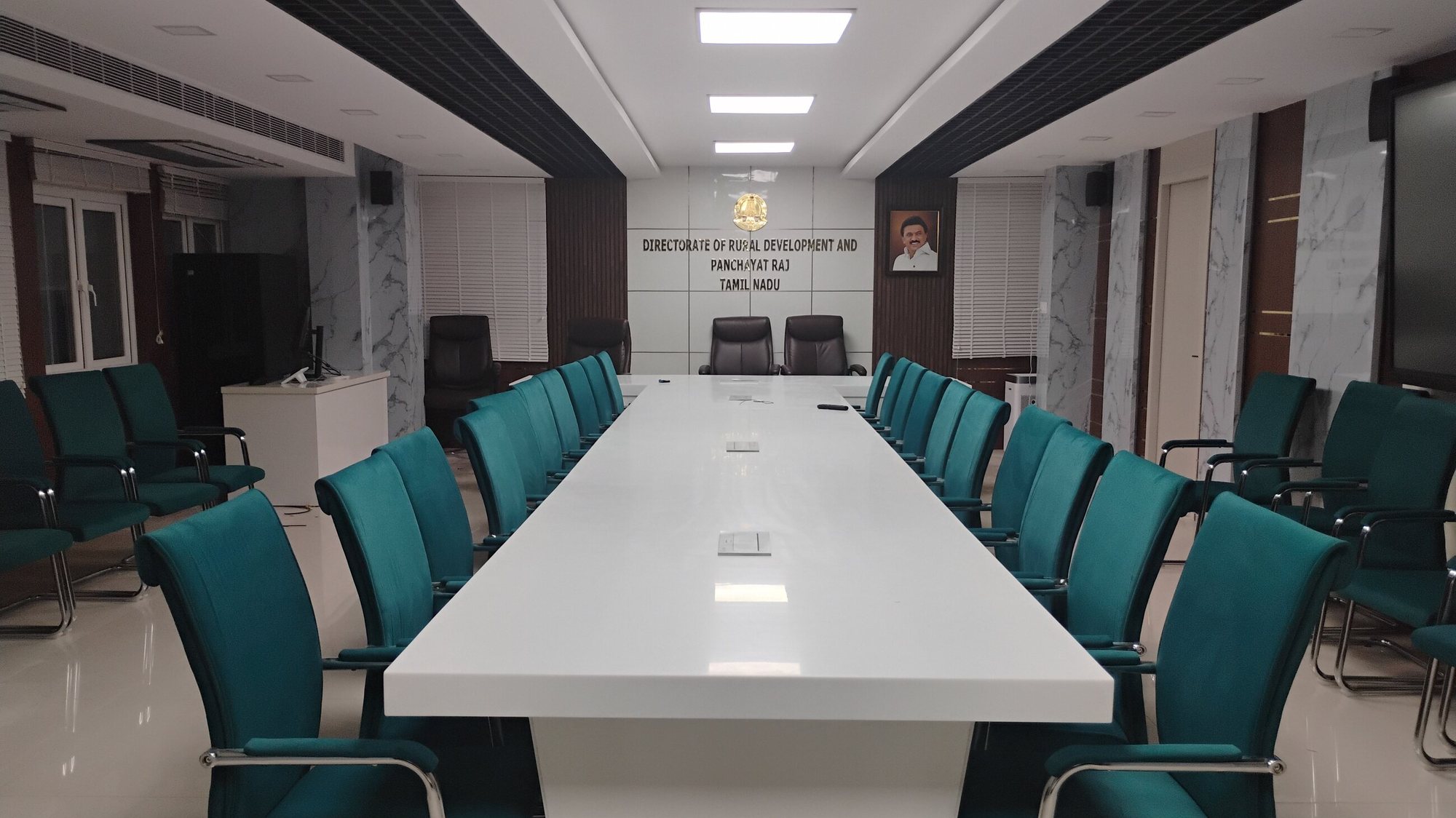 Board room with a long white table and teal chairs