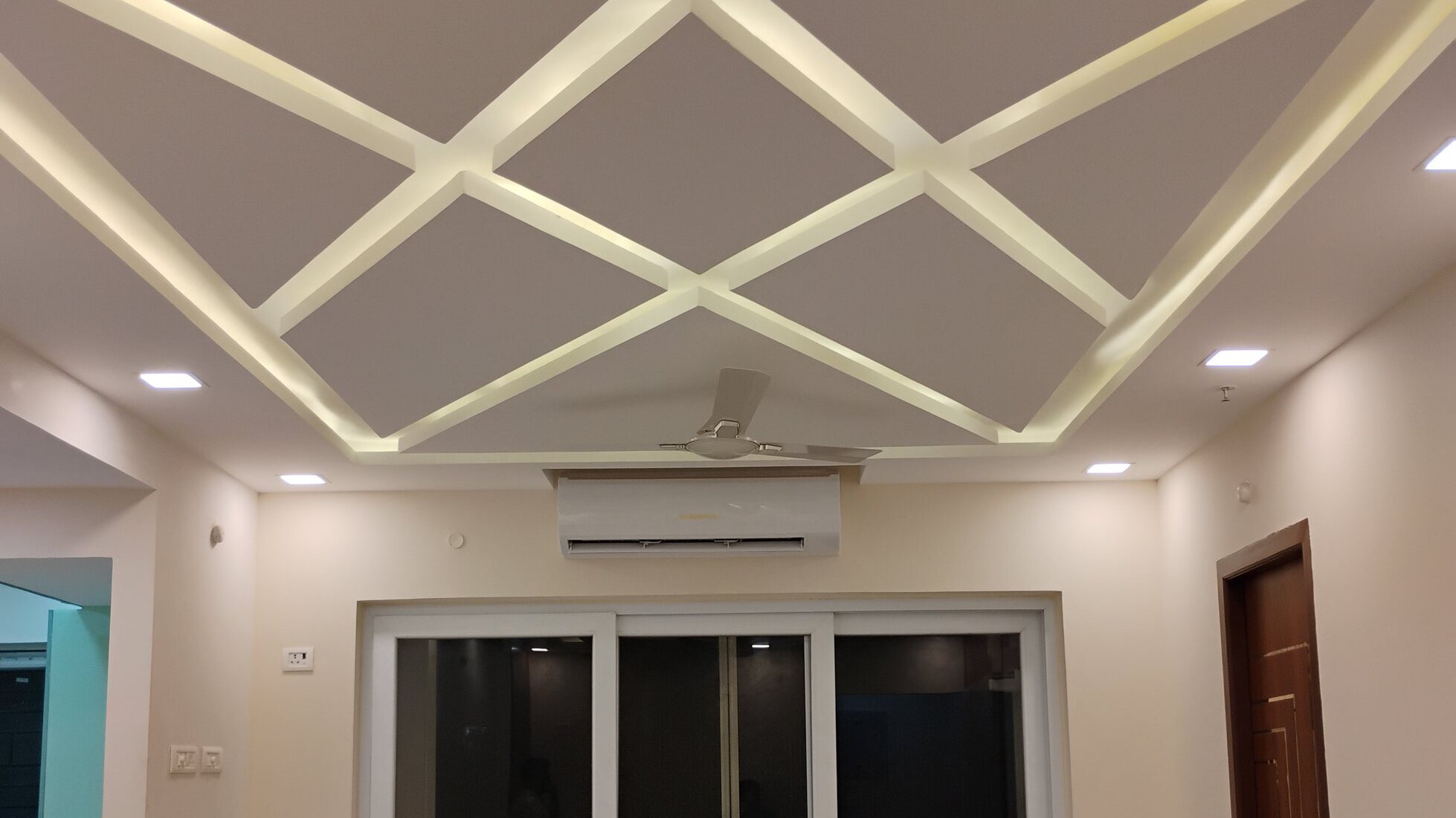 Apartment living area with a criss-cross false ceiling and cove lighting